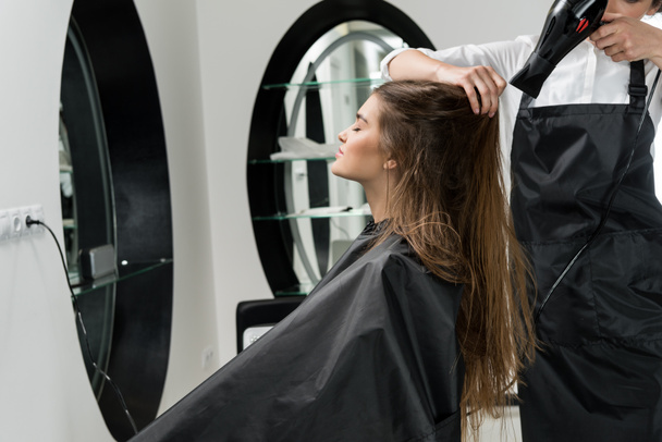 парикмахер сушит волосы женщины
 - Фото, изображение