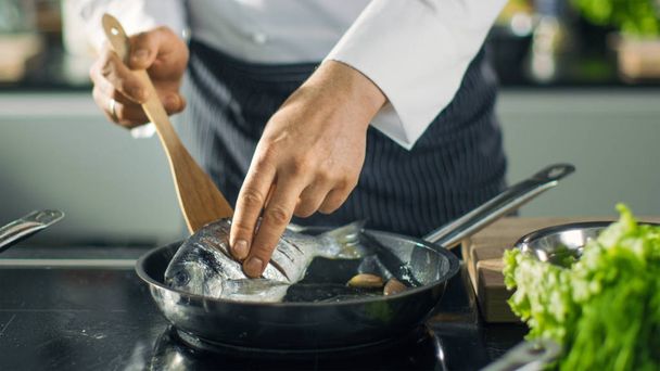 Le célèbre chef de restaurant retourne du poisson dans une casserole chaude. Gros plan Sh
 - Photo, image