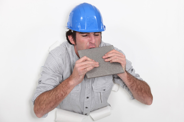 Fed-up tradesman biting a tile - Photo, Image