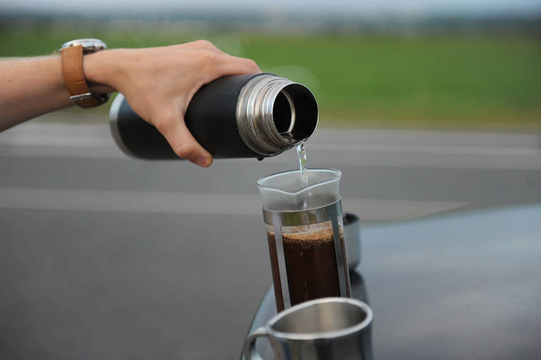 alternatives Kaffeeaufbrühen in einer französischen Presse auf der Motorhaube eines Autos am Straßenrand auf einer Reise - Foto, Bild
