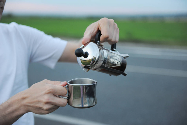 Альтернативное варение кофе во французском прессе на капоте автомобиля на обочине дороги в пути
 - Фото, изображение