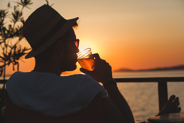Jeune homme profitant du coucher de soleil dans un bar de plage
 - Photo, image