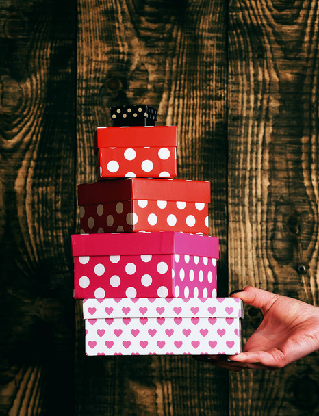 colorful spotted present box in female hand on wooden background - Foto, imagen