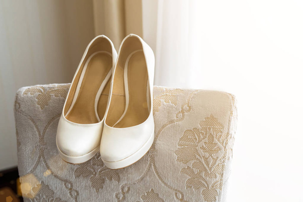 Свадебная обувь на спинке кресла возле окна
 - Фото, изображение