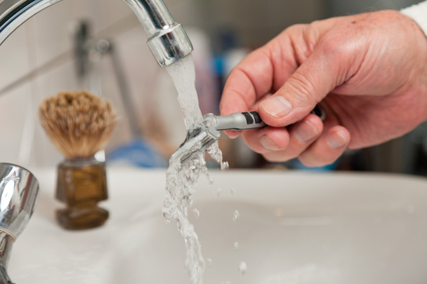 Closeup of hand cleaning shaving blade. - Фото, изображение