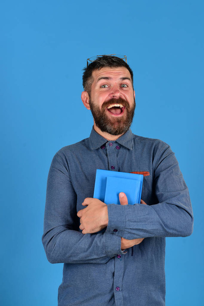 Textbook in blue color in guys hands on blue background - Photo, Image