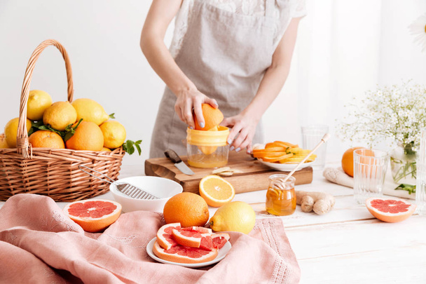 Cropped image of woman squeezes out juice of a citruses. - Foto, Bild