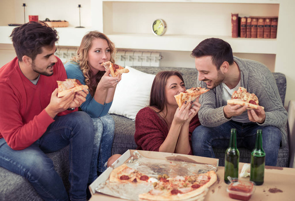 Grupa młodych przyjaciół jedzących pizza.Home party. - Zdjęcie, obraz