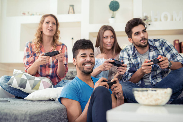 улыбающиеся друзья, играющие в видеоигры дома
 - Фото, изображение