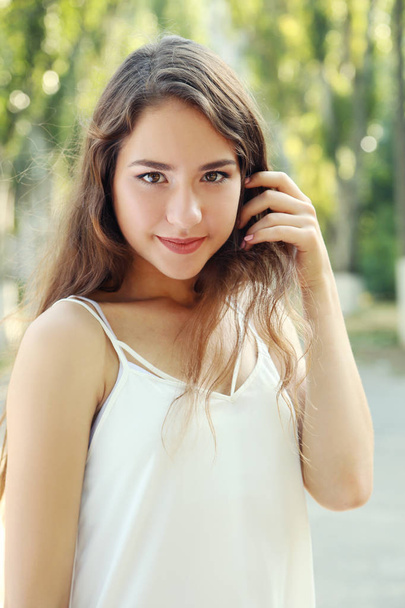 Portrait of beautiful young woman in park - Фото, изображение