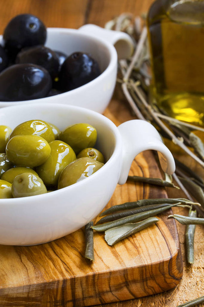 Olives vertes et noires à l'huile d'olive sur panneau rustique en bois .Ital
 - Photo, image