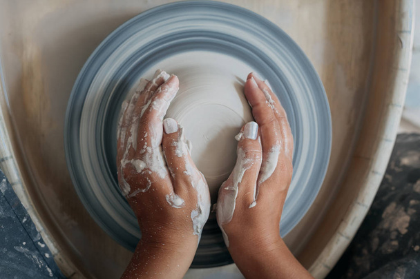 Vista superior da roda de cerâmica com as mãos da mulher, mãos sujas de oleiro
 - Foto, Imagem