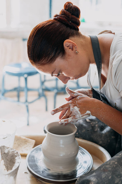 Молода жінка працює з керамічним колесом
 - Фото, зображення