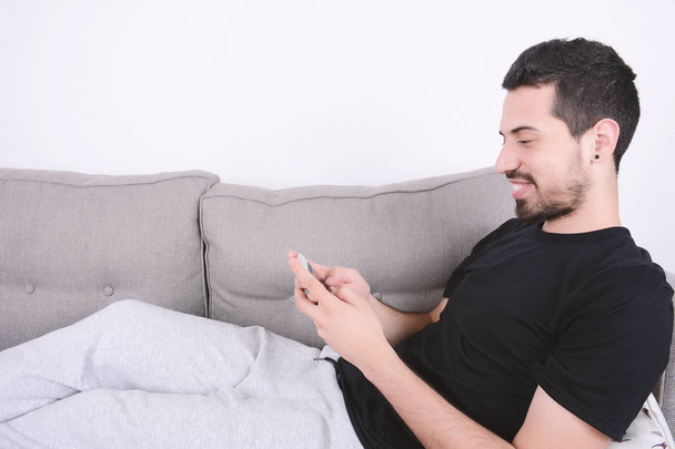 Man using smartphone on couch. - Foto, Imagem