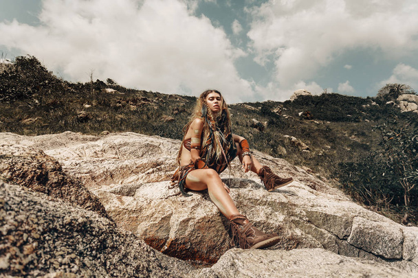 wild amazon woman sitting on the rocks outdoors - Fotoğraf, Görsel