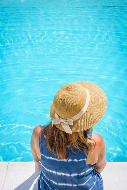 vrouw in sunhat zitten aan het zwembad - Foto, afbeelding