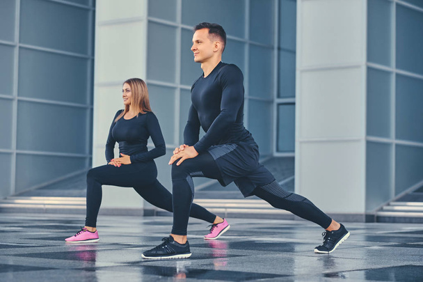 Couple stretching over modern building - Photo, Image