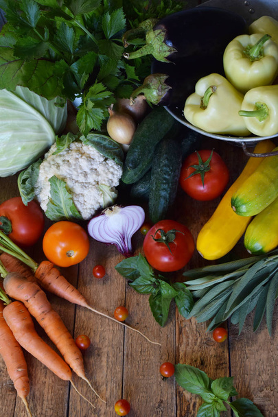 Concepto de alimento biológico. Ingredientes para una cocina saludable. Verduras y hierbas sobre fondo de madera. Preparación de platos de abbage, pepino, zanahoria, calabacín, pimienta, cebolla, berenjena, tomate
 - Foto, Imagen