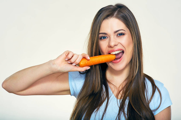 woman bites carrot. Isolated studio portrait. - Foto, afbeelding