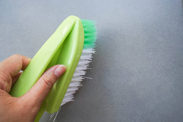 primo piano mano con spazzola di lavaggio verde sul pavimento tessile per la pulizia
 - Foto, immagini
