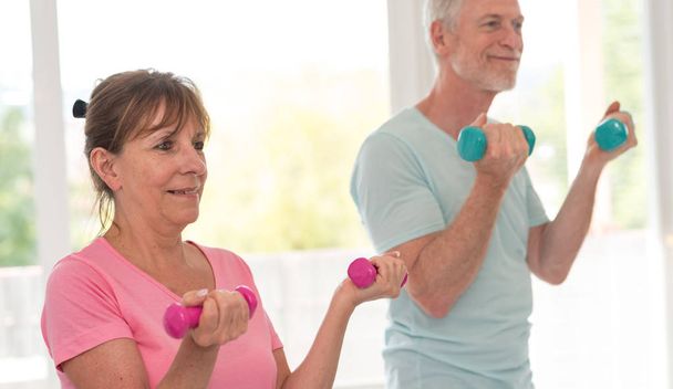 Senior couple exercising with dumbbells - Foto, afbeelding