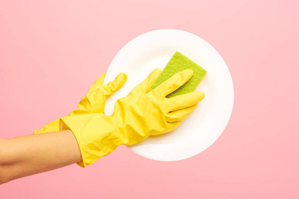 Hands in yellow protective gloves washing a plate - Фото, изображение