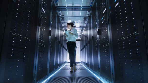 Female IT Engineer Walking through Data Center Corridor. She is  - Zdjęcie, obraz