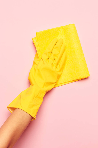 The womans hand cleaning on a pink background. Cleaning or housekeeping concept - Zdjęcie, obraz