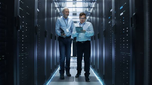 In Data Center Two IT Engineers Walking Through Rows of Server R - Valokuva, kuva