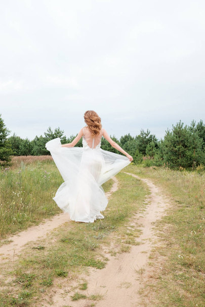 young pretty woman (bride) in white wedding dress outdoors runni - Foto, Imagen