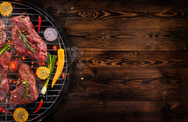 Top view of fresh meat and vegetable on grill placed on wooden p - Photo, Image