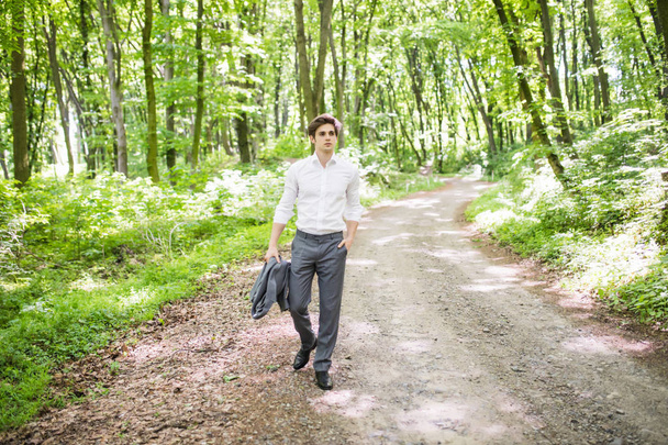 Beau homme d'affaires confiant en costume marchant dans un parc vert. Concept d'entreprise
. - Photo, image