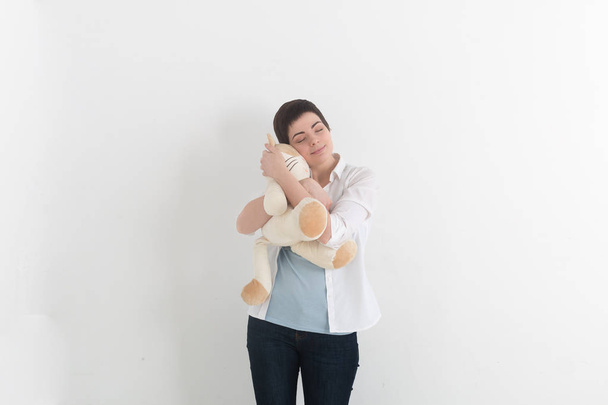 Childish young woman hugging soft plush cat with innocent smile and closed eyes. Sweet dreams. - Foto, Bild