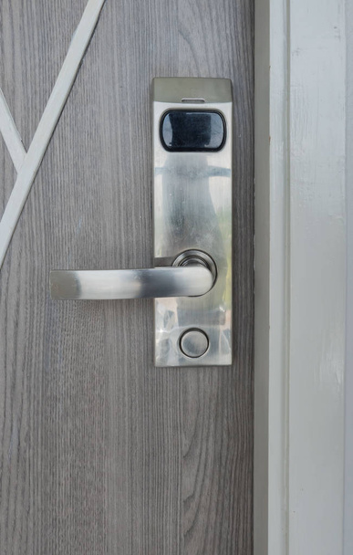 Γκρο πλαν ηλεκτρονικό κλειδί κλειδαριά της πόρτας σε μια ξύλινη πόρτα γκρι  - Φωτογραφία, εικόνα
