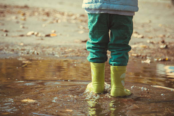 少年をゴム長靴で水たまりを歩く - 写真・画像