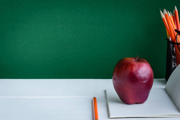 Livros Lápis e maçã sobre uma mesa de madeira branca
 - Foto, Imagem