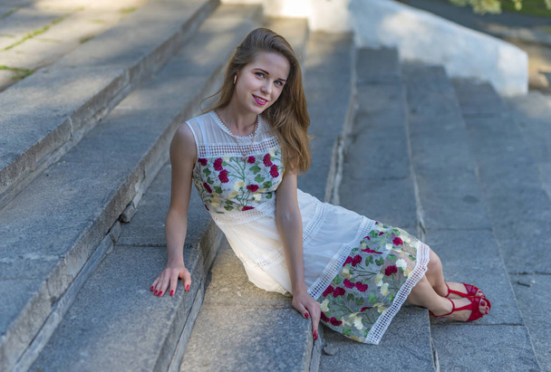 schönes Mädchen sitzt auf steinernen Stufen  - Foto, Bild