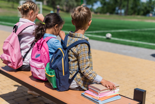 schoolkinderen met boeken zitten op bankje - Foto, afbeelding