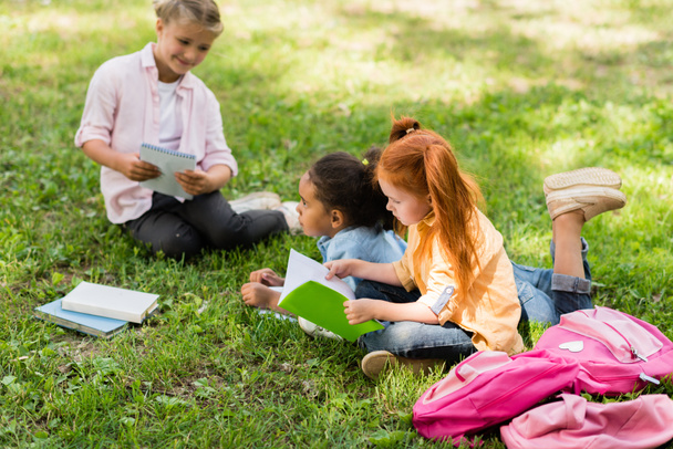 multiethnic schoolgirls studying on grass - Zdjęcie, obraz
