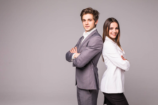 Full length of two young business people standing back to back with hands crossed isolated on grey background - Foto, afbeelding