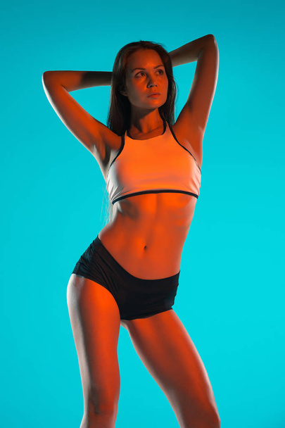 Muscular young woman athlete posing at studio - Photo, image