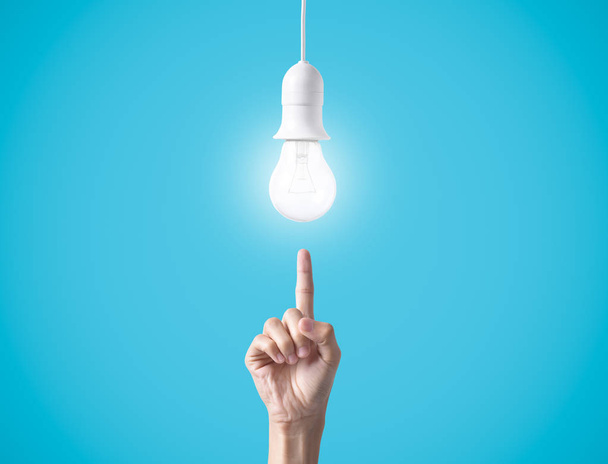 Business hand point light bulb on blue background.  - Photo, Image