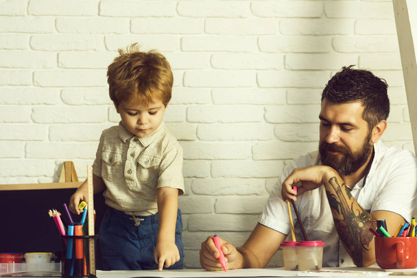 Χαρούμενη ώρα οικογένεια, σχέδιο με πατέρα του στο τραπέζι, ελεύθερος χρόνος και διακοπές για την τέχνη και τη δημιουργικότητα. Αγόρι και δάσκαλος συνεργάζονται στην εικόνα στο σχολείο. Το παιδί δε δείχνει δάχτυλο χρώμα μοτίβο - Φωτογραφία, εικόνα