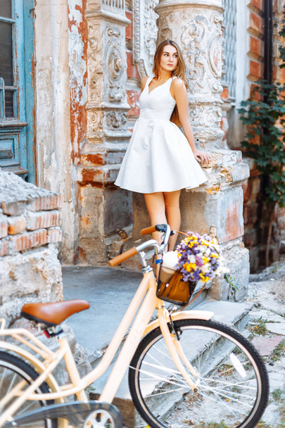 Όμορφο κορίτσι με ένα ποδήλατο κοντά σε μια παλιά πόρτα μπλε - Φωτογραφία, εικόνα