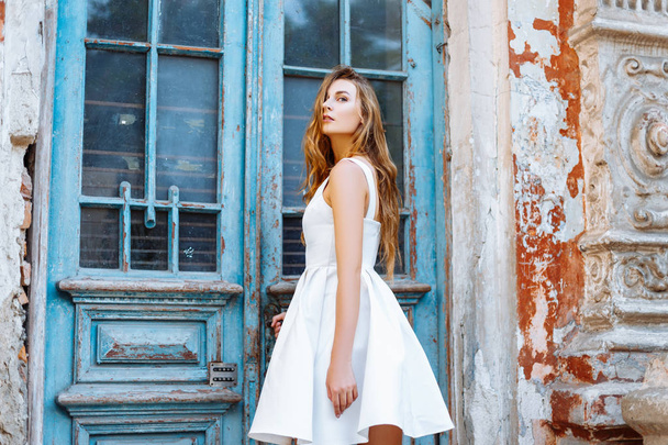 Beautiful girl in a white dress near a blue door - Photo, Image