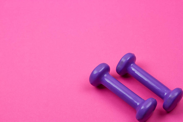 Purple dumbbells on a pink background - Photo, Image