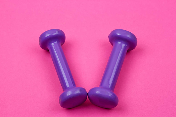 Фиолетовые гантели на розовом фоне
 - Фото, изображение