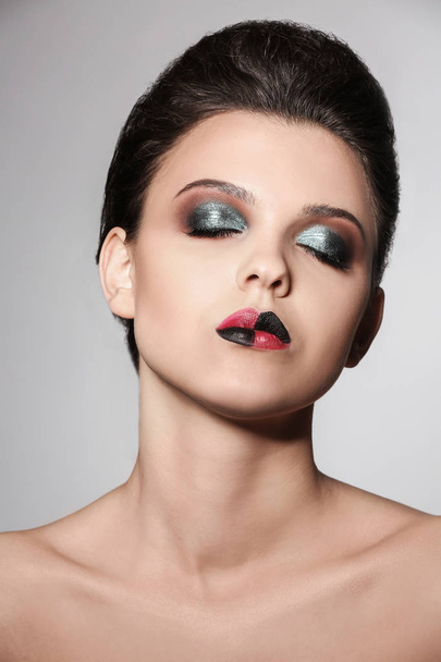 Beautiful young woman with creative makeup on light background - Valokuva, kuva