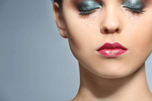 Beautiful young woman with creative makeup on color background, closeup - Fotó, kép