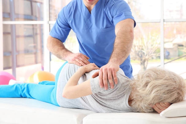 Physiotherapist working with elderly patient in clinic - Foto, Bild